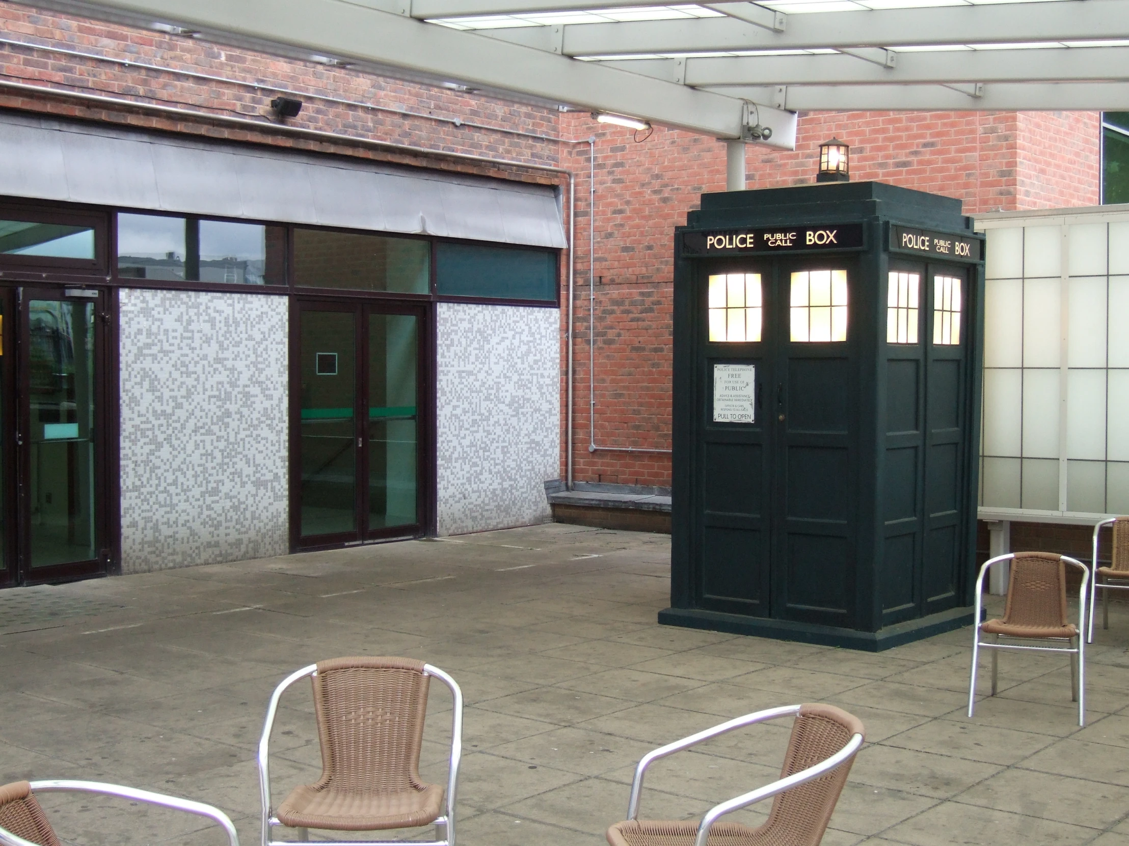 a blue phone booth is in the middle of a courtyard