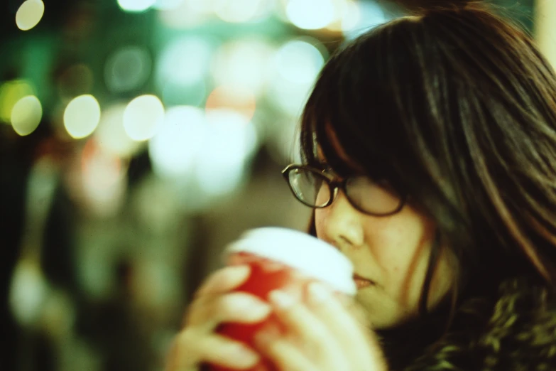 a woman holding a cup with a cell phone next to her