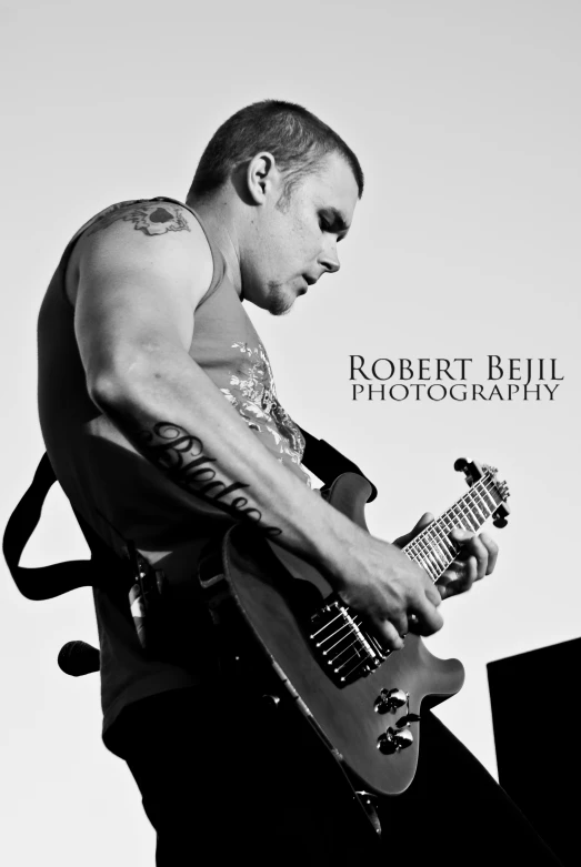 black and white pograph of male in black and white playing a guitar