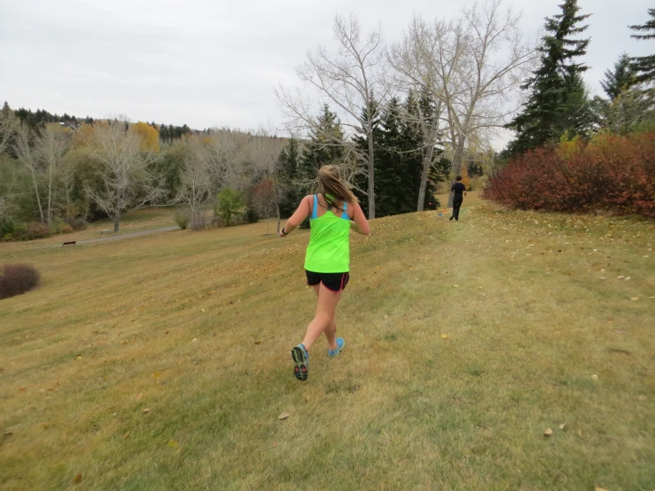 a woman in neon vest running in a grassy field