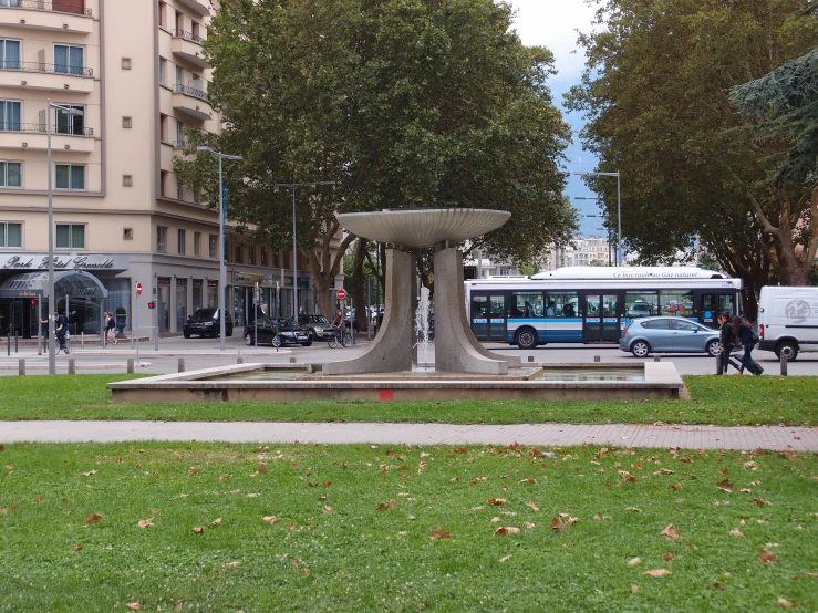 two buses are parked beside a stone fountain