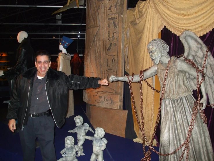 a man in a black jacket and some statues