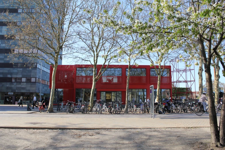a red building next to tall brick buildings with bicycles parked in front