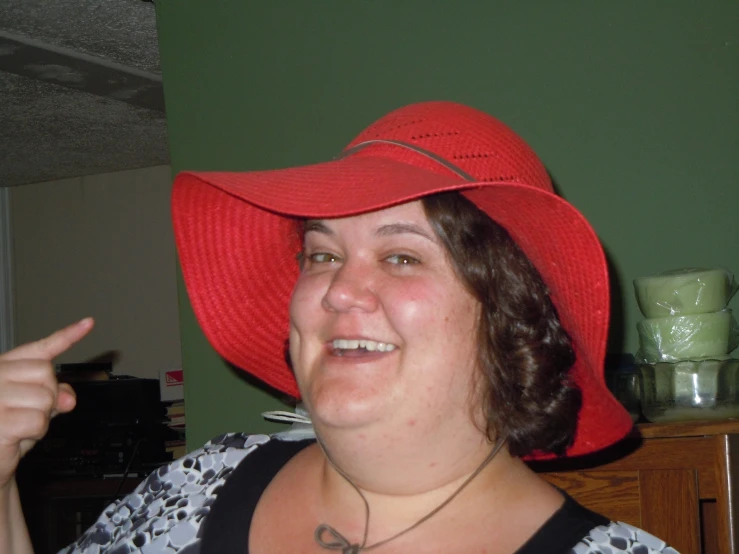 a woman in a red hat smiles and points