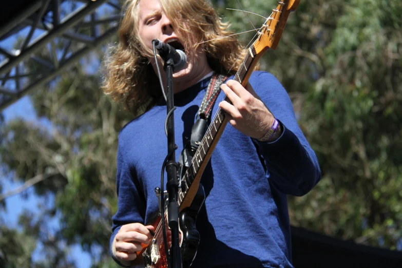 a person playing the guitar while singing into a microphone