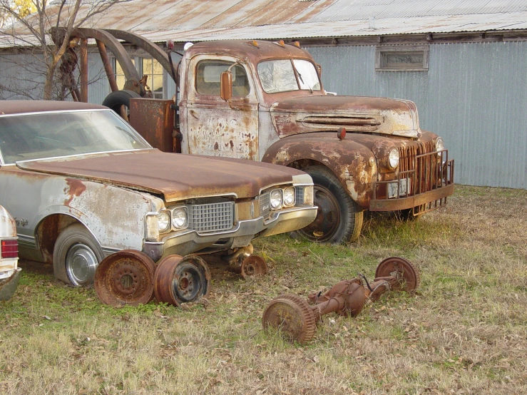 an old rusty truck and some other broken down vehicles