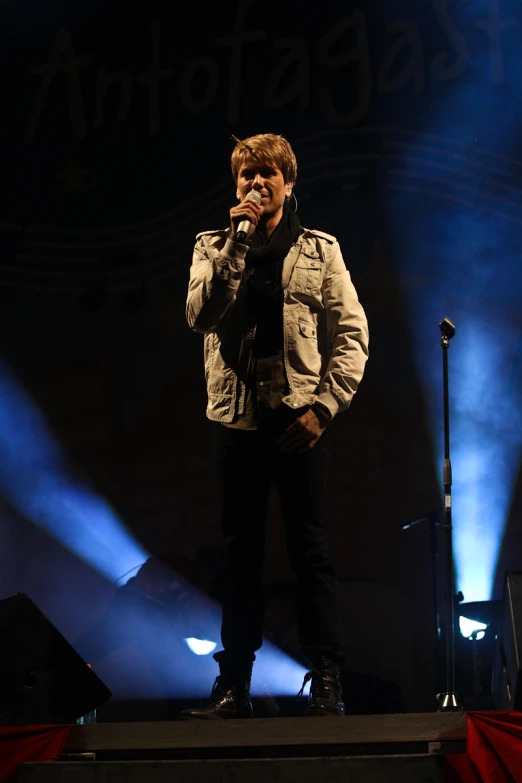 a man on stage with microphone, in front of bright lights