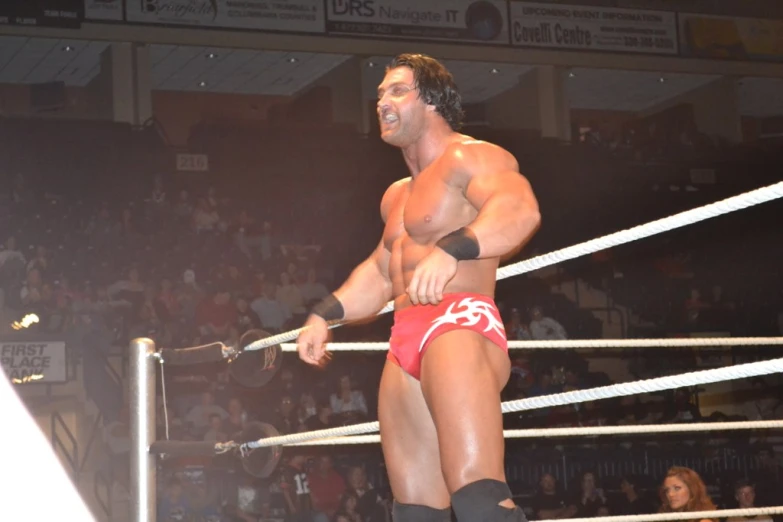 wrestler in red trunks and black boots holding an axe