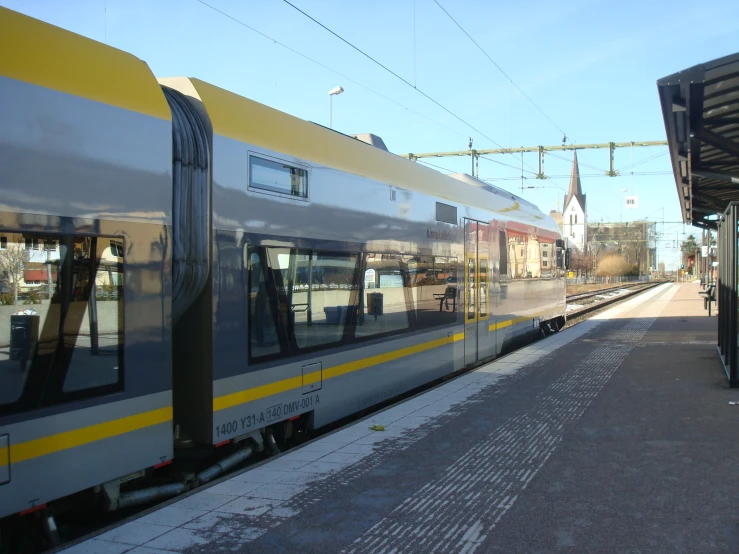 a silver and yellow train pulling into a station