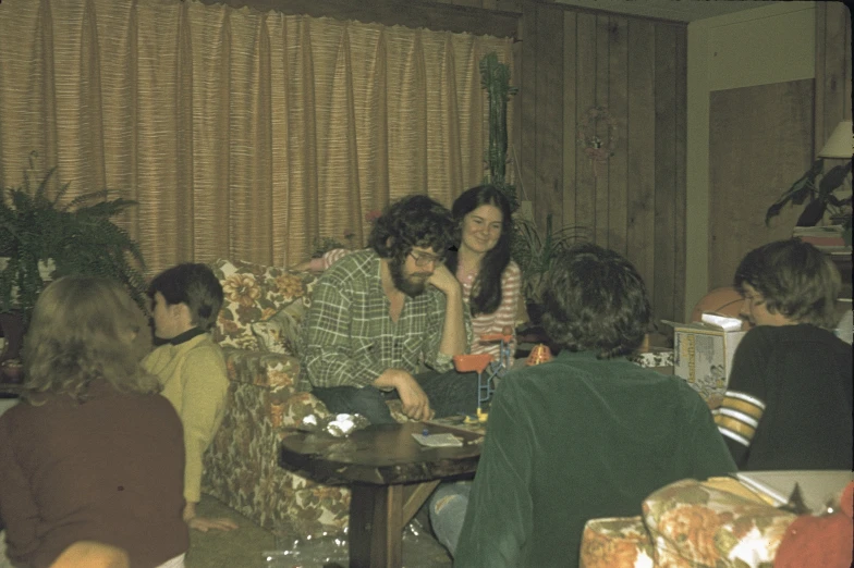 a group of people sitting and standing around in the living room