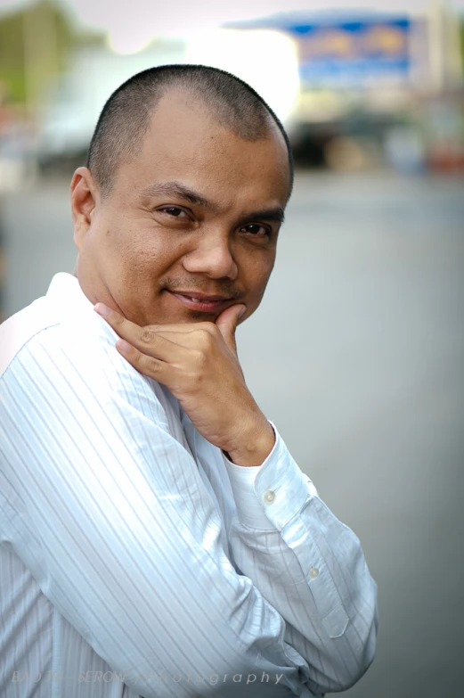 a man poses for the camera while wearing a white striped shirt