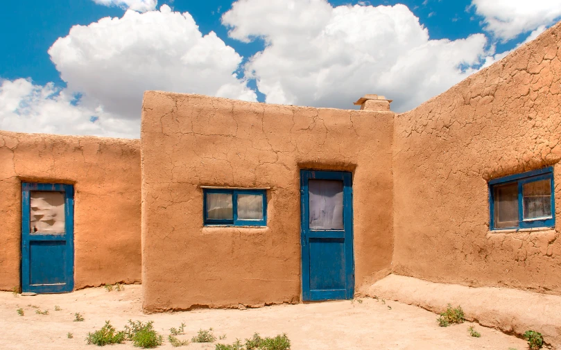 two adobe homes with blue door on a cloudy day