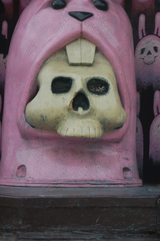 a skull shaped sculpture is on display in front of an image of a face