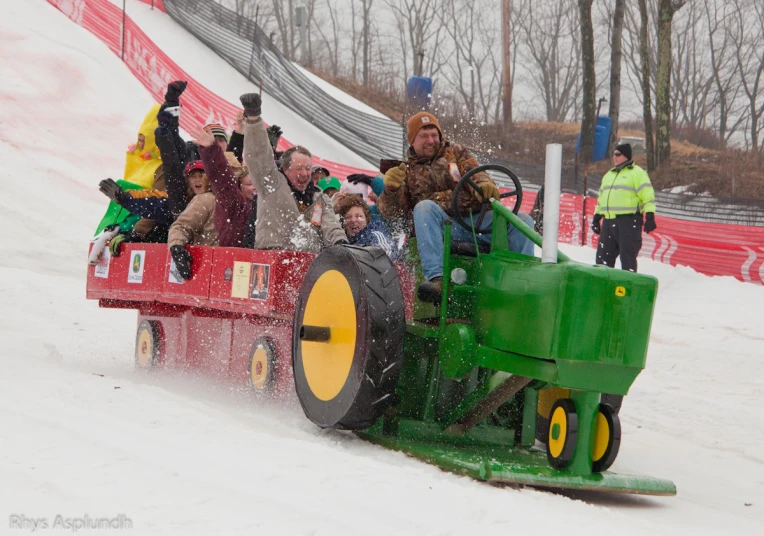 several people watching soing driving on a green and yellow vehicle