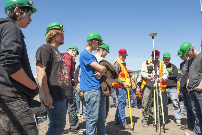 people wearing hard hats while standing on the dirt