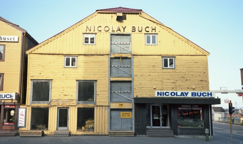 a shop front with yellow painted wood, window shutters and a sign