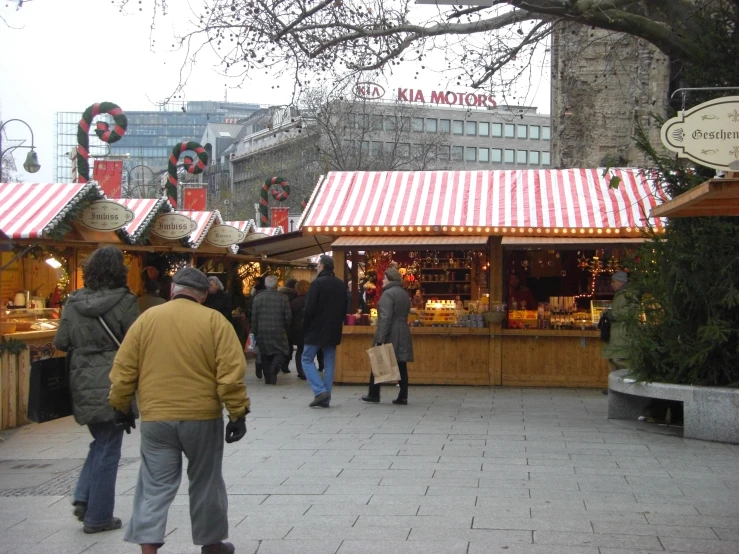 people are walking near a food stand at a plaza