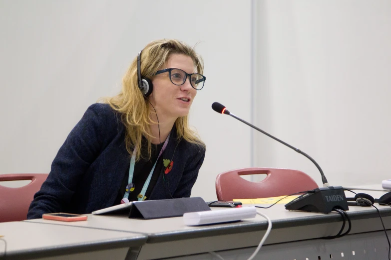 the woman in glasses is speaking to the speakers