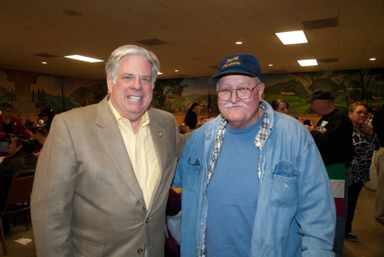 two men standing next to each other in front of people