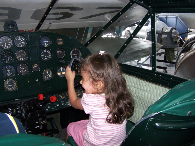 a girl sitting inside of an airplane plane with other pilots