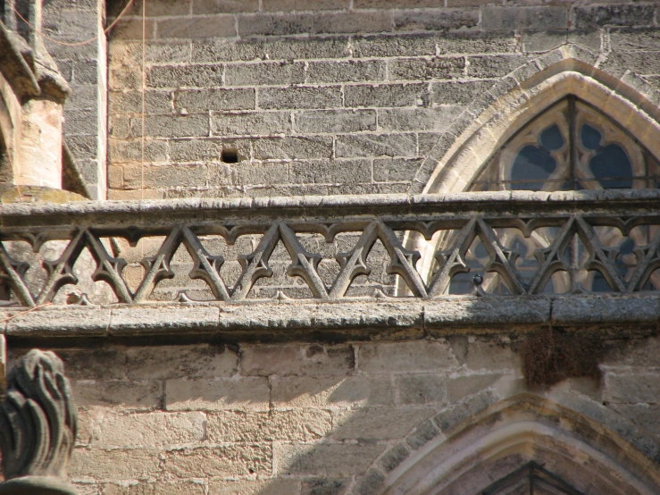 the upper part of a building, showing the side view of a large window and an iron balcony