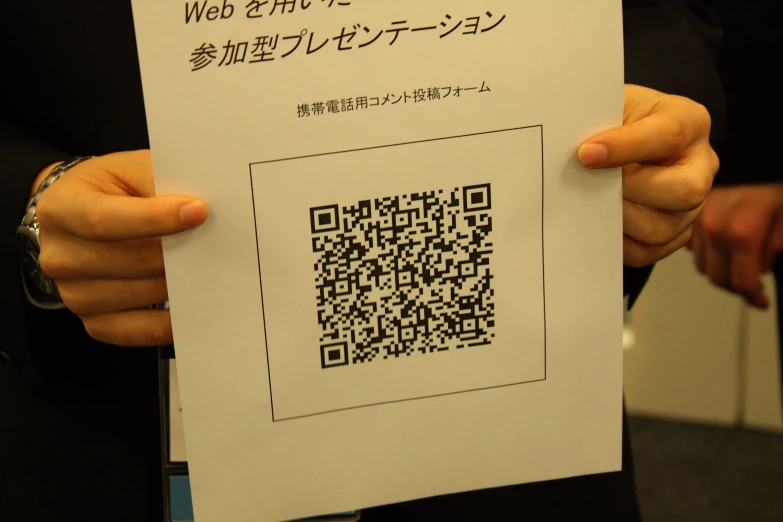 a person holding up a piece of paper with an image of a qr code