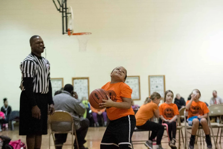 a group of young people sitting on top of a basketball court