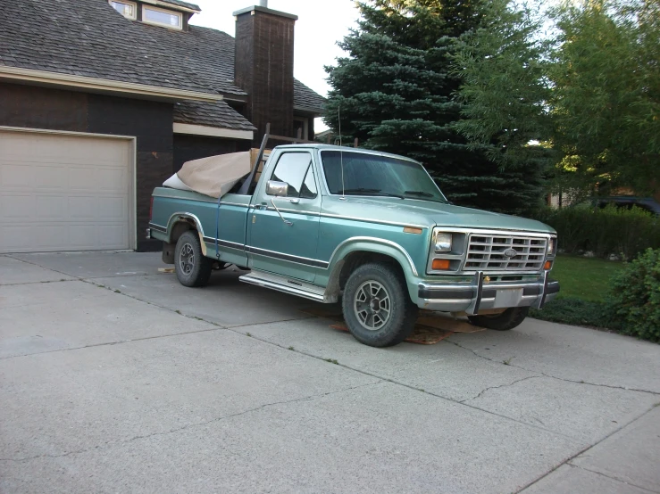 a green pick up truck parked in front of a house