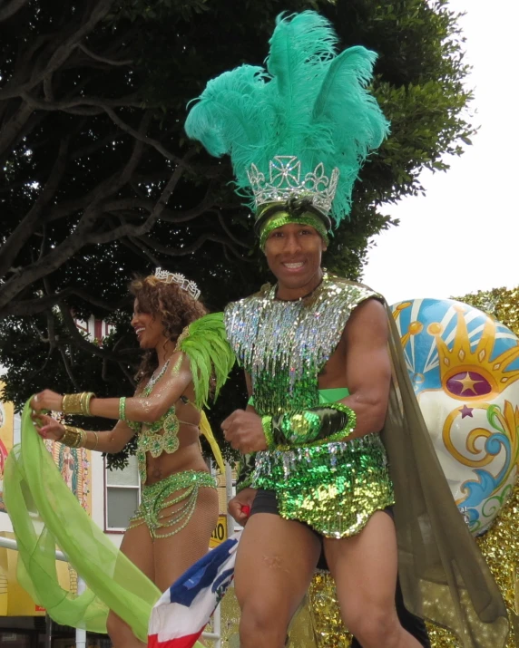 two dancers at a carnival, some with green headdreses