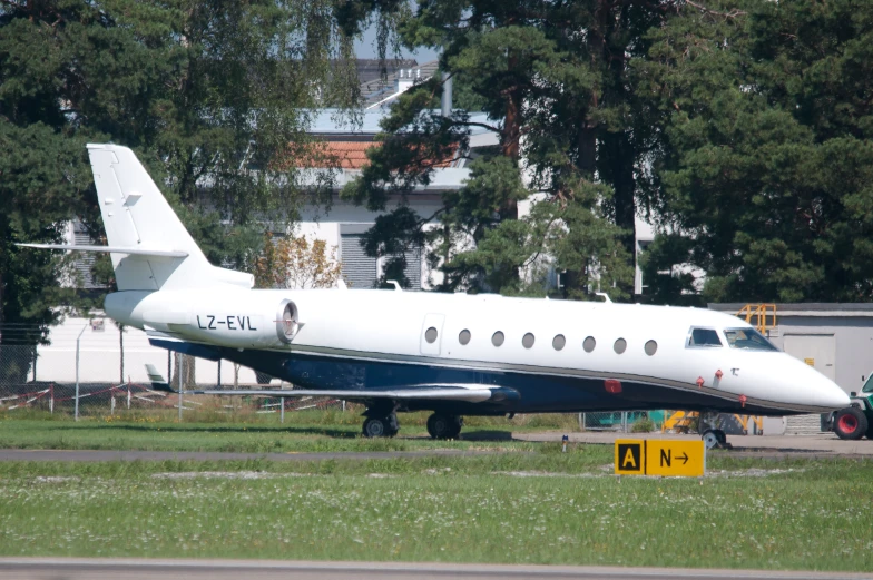 an airplane sitting parked near a road in front of some trees