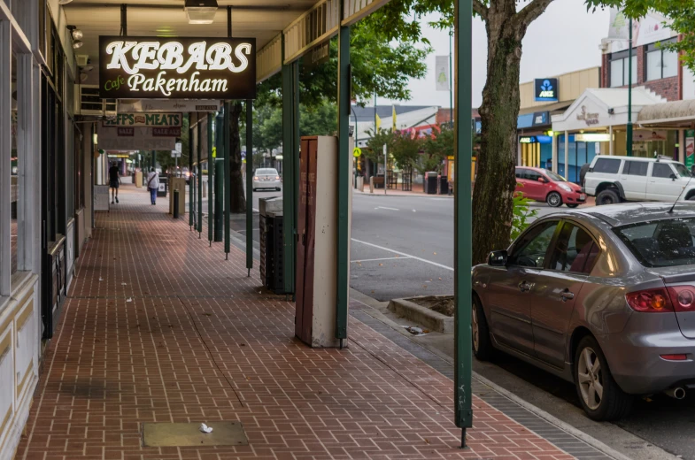 a city sidewalk with cars parked on the side of it