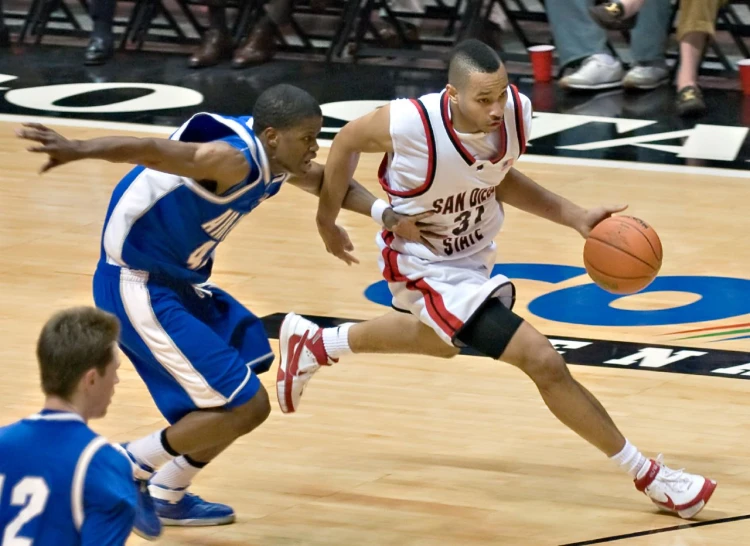 two basketball players colliding with the ball during a game
