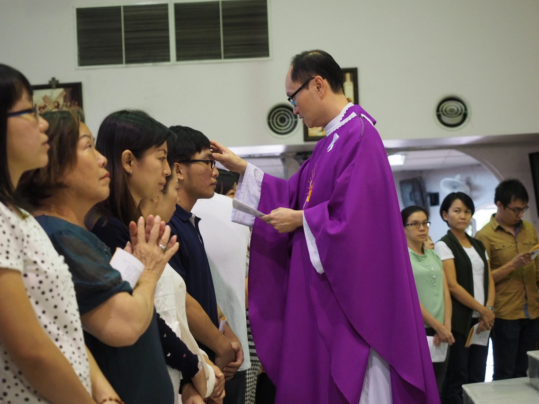 a priest standing before several people at a congregation