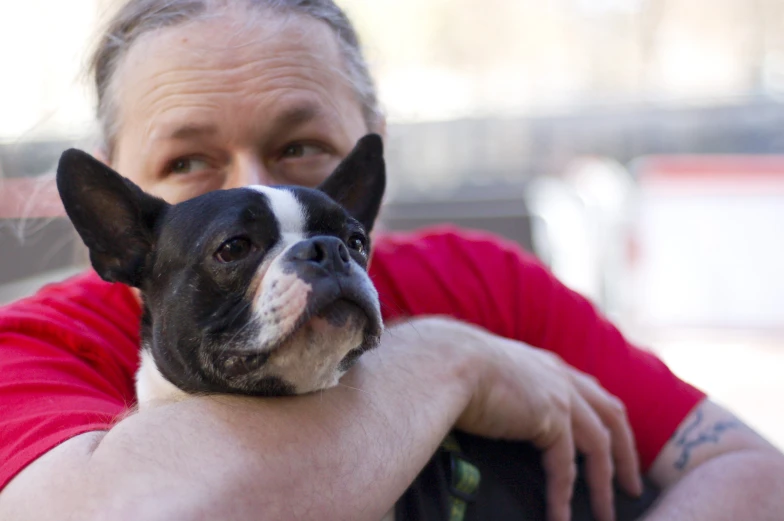 a woman wearing red holds her dog in the arms