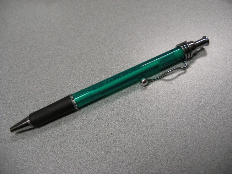 a green and black ballpoint pen sitting on top of a table
