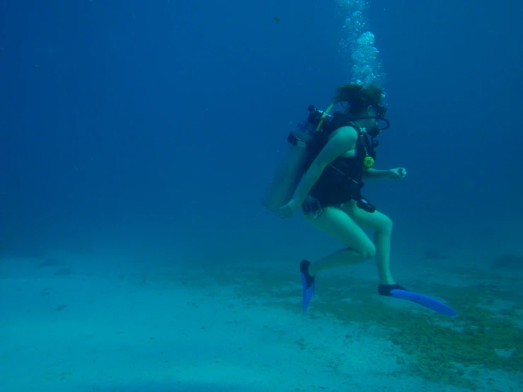 a man scubas in blue water with a small group of divers behind him