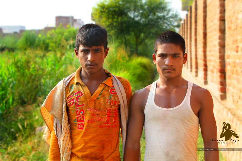 two boys standing next to each other with their shirts on