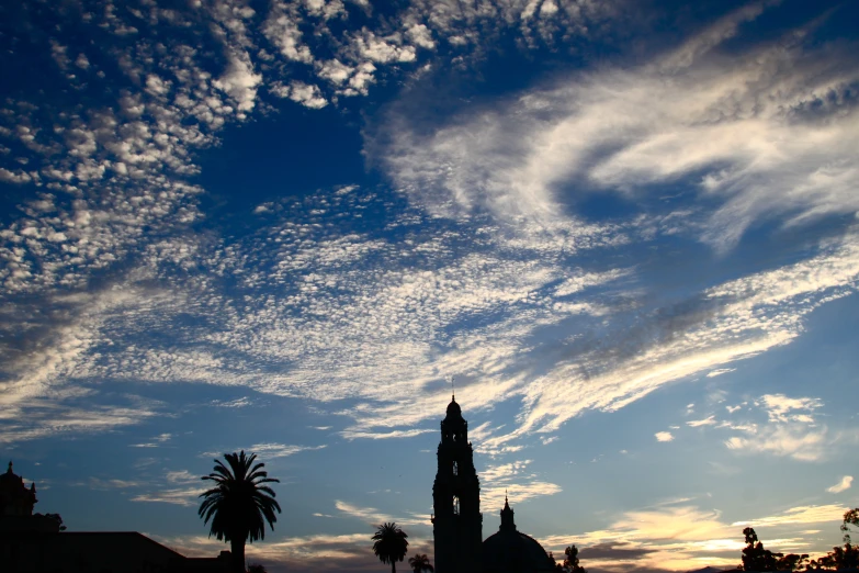 a large clock tower with an obelisk on it and palm trees near by