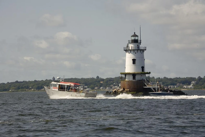 there is a large boat riding in the water with a light house on top