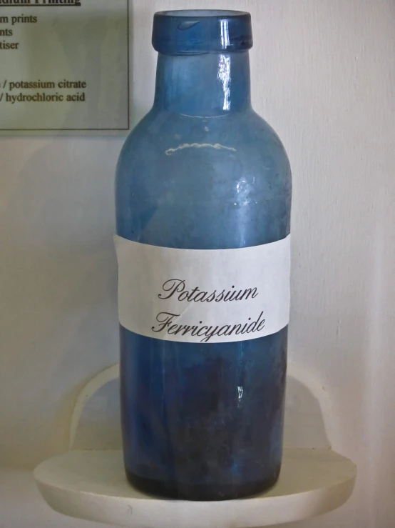 a blue jar with a white label sitting on a wall