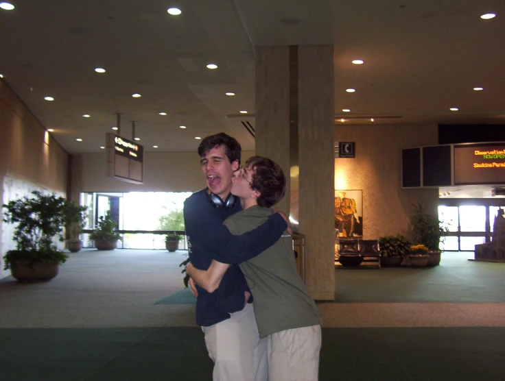 two people are kissing inside an atrium with lighting and columns