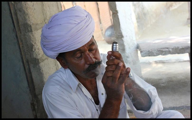 a man in a turban holds an electronic device