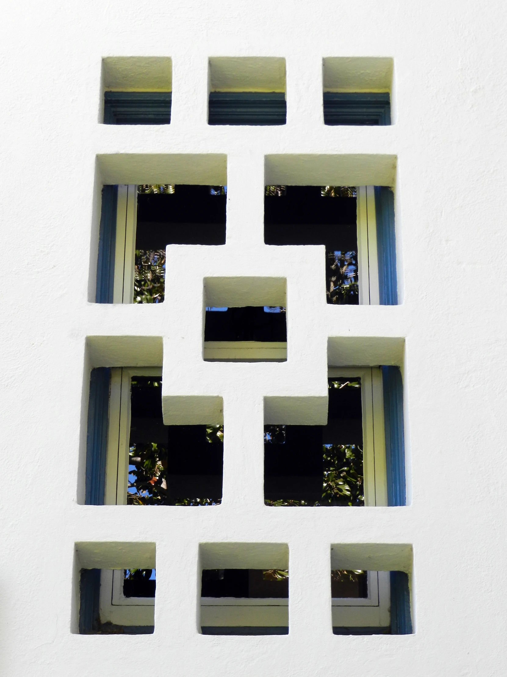 a wall with many windows has a reflection of trees