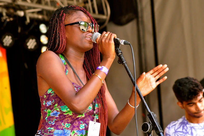 woman in purple top singing into microphone with man in background