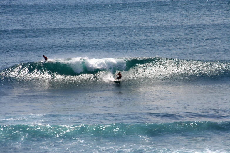 two surfers riding waves in the ocean near another