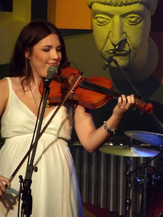 a woman holding her violin in front of a microphone