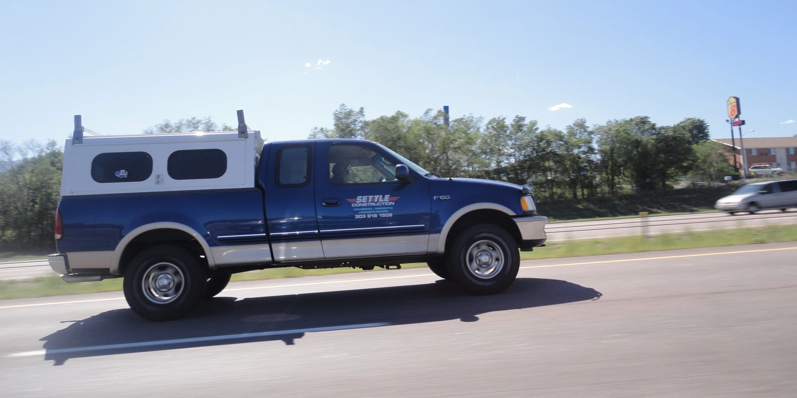 a blue truck with a white tailpipe driving down the road