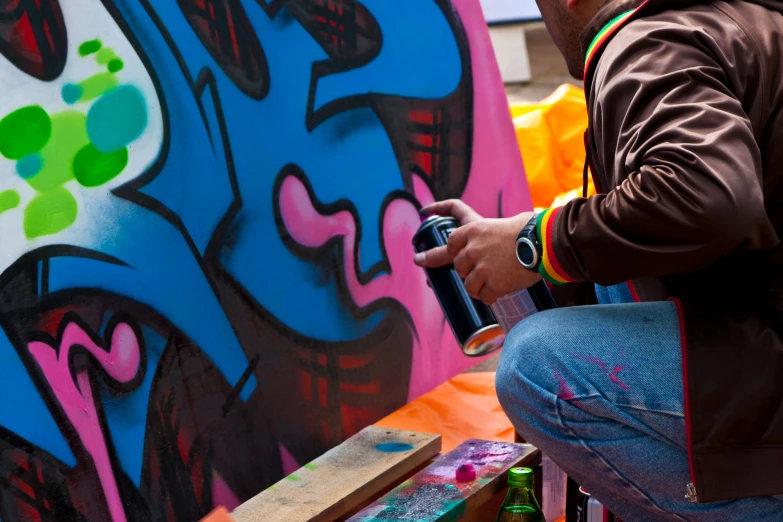 person painting on side of wall with colorful background