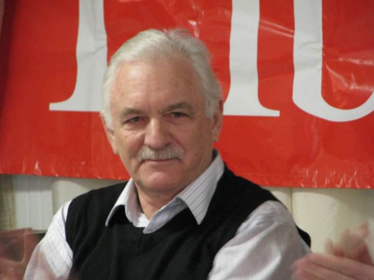 a man with white hair wearing a vest