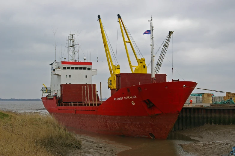 a red cargo ship sitting on top of a dry river